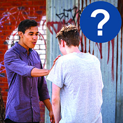 One young man is holding out his hand. He is trying to stop another young man. There is a circle with a question mark.
