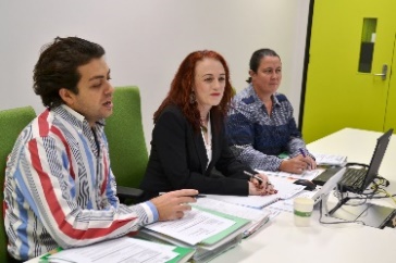 three people sitting at a table discussing something